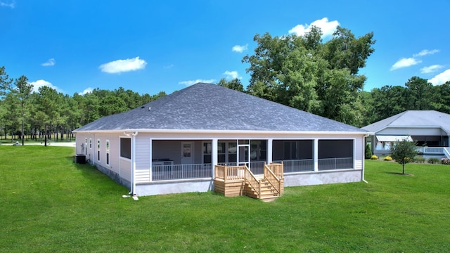 rear view of house featuring a lawn and a sunroom