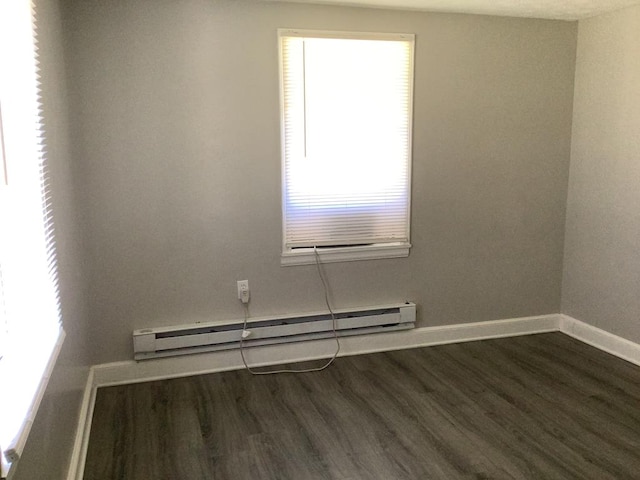 spare room with dark wood-style floors, baseboard heating, and baseboards