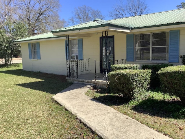 property entrance featuring metal roof, concrete block siding, a porch, and a yard