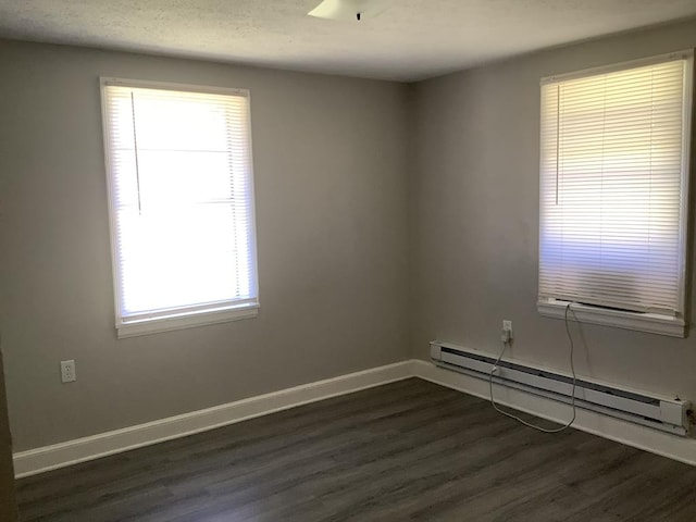 unfurnished room featuring a baseboard heating unit, dark wood-style flooring, a textured ceiling, and baseboards