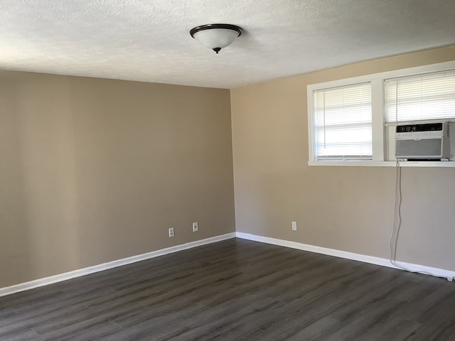 spare room featuring a textured ceiling, baseboards, dark wood finished floors, and cooling unit