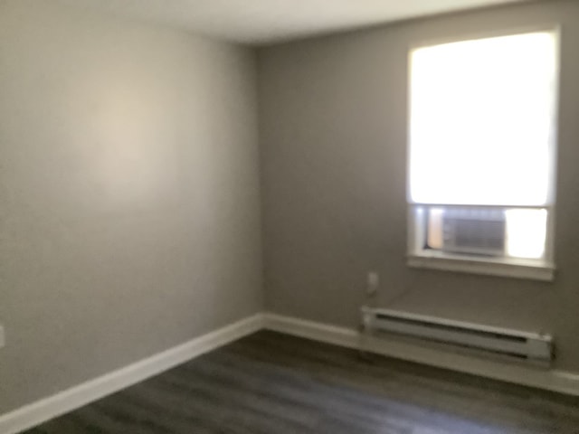 unfurnished room featuring dark wood-type flooring, baseboard heating, cooling unit, and baseboards