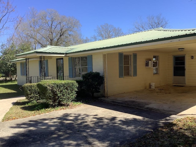 view of front of property featuring metal roof, concrete driveway, a carport, and covered porch