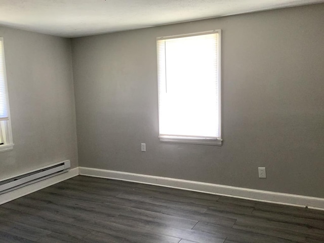 empty room with baseboard heating, dark wood finished floors, and baseboards