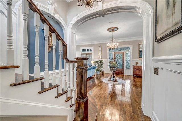 entrance foyer with hardwood / wood-style floors, ornamental molding, and a chandelier