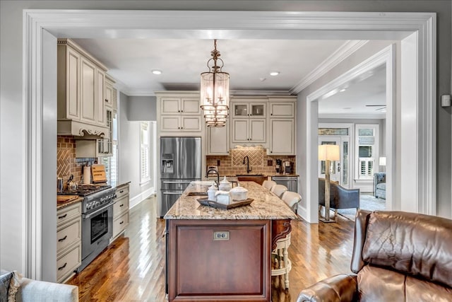 kitchen with pendant lighting, cream cabinetry, appliances with stainless steel finishes, and tasteful backsplash