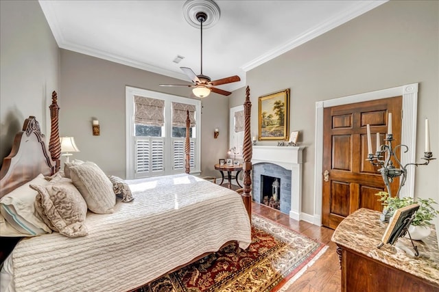 bedroom with crown molding, a brick fireplace, light wood-type flooring, and ceiling fan