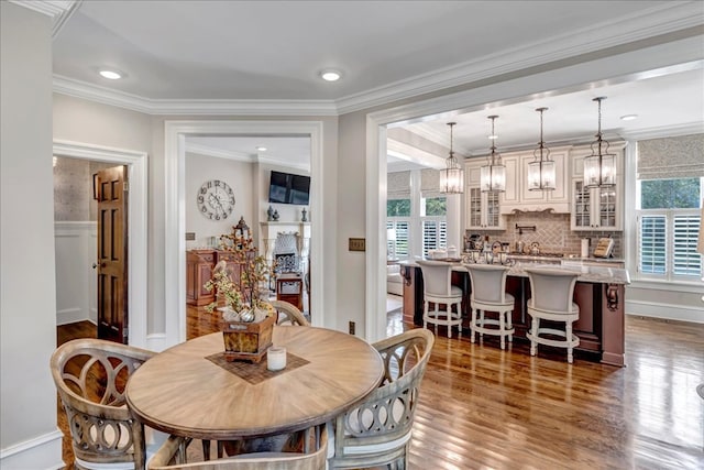 dining area with dark hardwood / wood-style flooring, ornamental molding, and an inviting chandelier