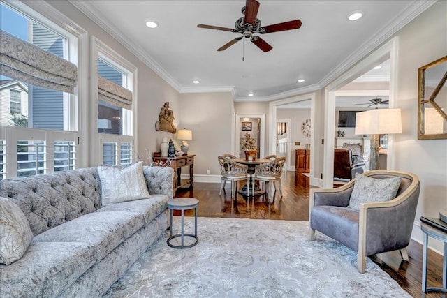 living room with hardwood / wood-style flooring, ceiling fan, ornamental molding, and plenty of natural light