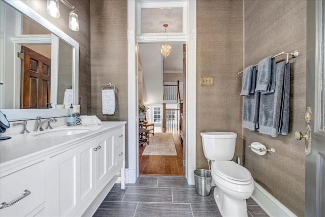 bathroom featuring toilet, vanity, and an inviting chandelier