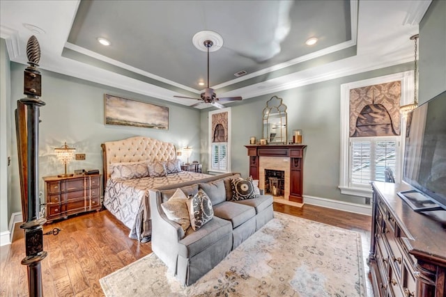 bedroom featuring ceiling fan, crown molding, a raised ceiling, and light wood-type flooring