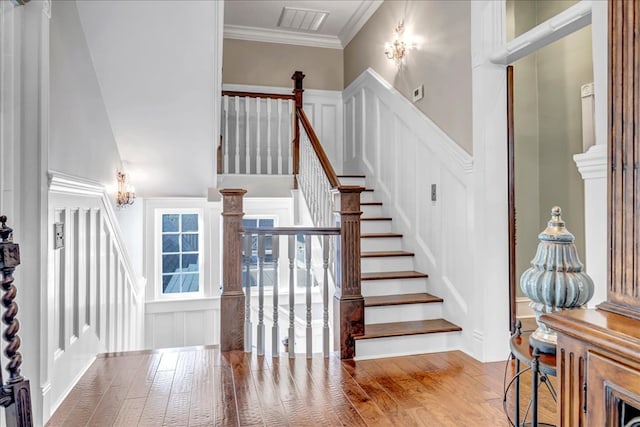 staircase featuring crown molding, hardwood / wood-style floors, and a notable chandelier