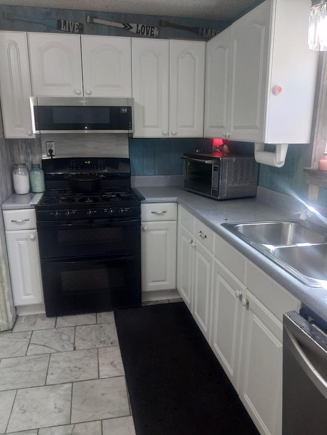 480 Spring Creek Rd, Warwick, GA 31796 - kitchen featuring appliances with stainless steel finishes, white cabinets, a sink, light countertops, and tasteful backsplash