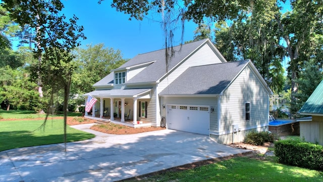 view of front of home with covered porch, a front yard, and a garage