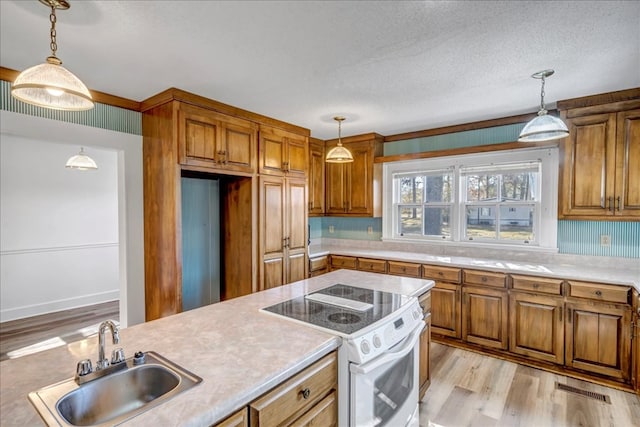 kitchen with sink, pendant lighting, light hardwood / wood-style flooring, and electric stove