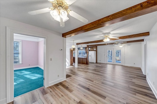 unfurnished living room with light hardwood / wood-style floors, plenty of natural light, a textured ceiling, and ceiling fan