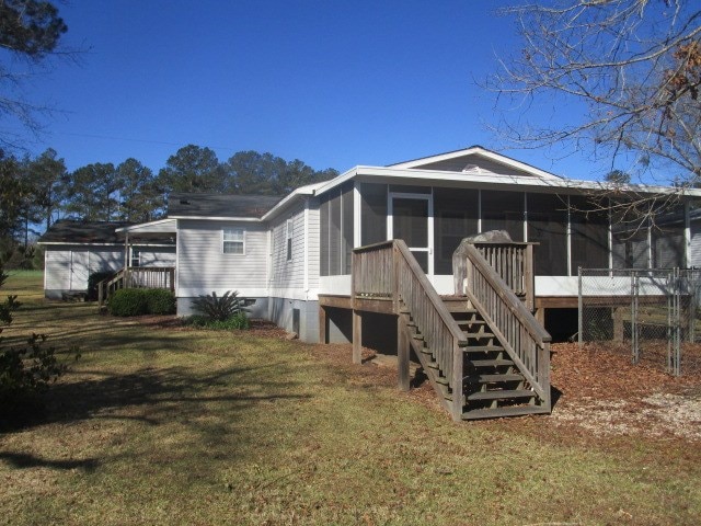 back of property featuring a lawn, stairway, and a sunroom