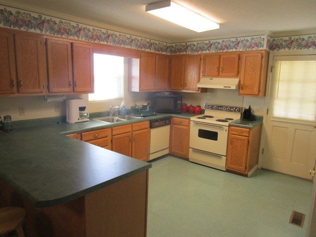 kitchen with light floors, dark countertops, a sink, white appliances, and under cabinet range hood