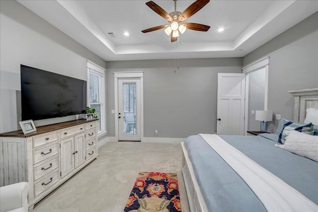 carpeted bedroom with ceiling fan, access to exterior, and a tray ceiling