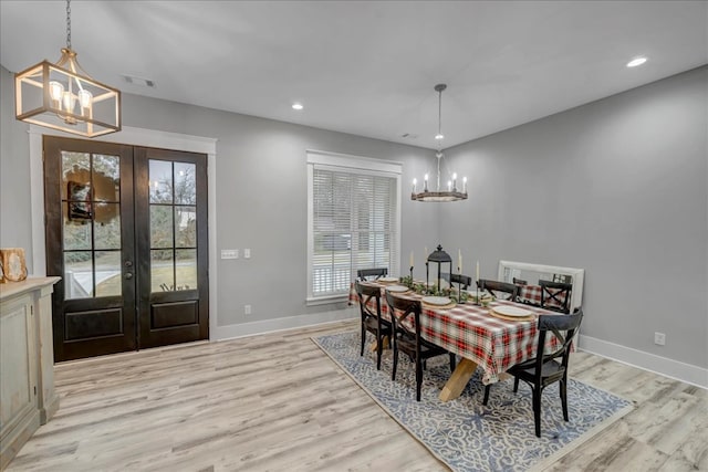 dining room with light wood-type flooring, french doors, and a chandelier