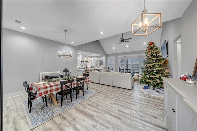 dining space with light hardwood / wood-style floors, ceiling fan with notable chandelier, and high vaulted ceiling