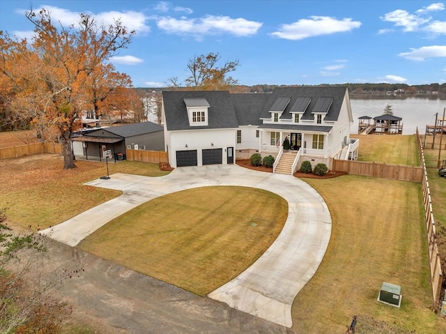 view of front of home featuring a garage, covered porch, a water view, and a front lawn