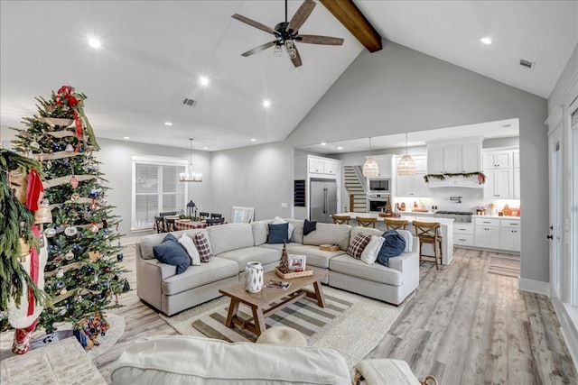 living room featuring ceiling fan with notable chandelier, beamed ceiling, light hardwood / wood-style flooring, and high vaulted ceiling