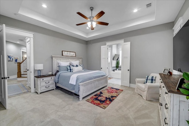 carpeted bedroom with ceiling fan, connected bathroom, and a raised ceiling