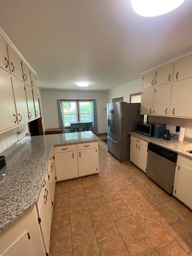 kitchen with light tile patterned floors, stainless steel appliances, a peninsula, and white cabinetry