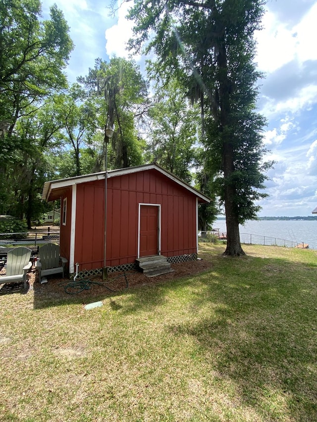 view of outbuilding featuring entry steps, fence, a water view, and an outdoor structure