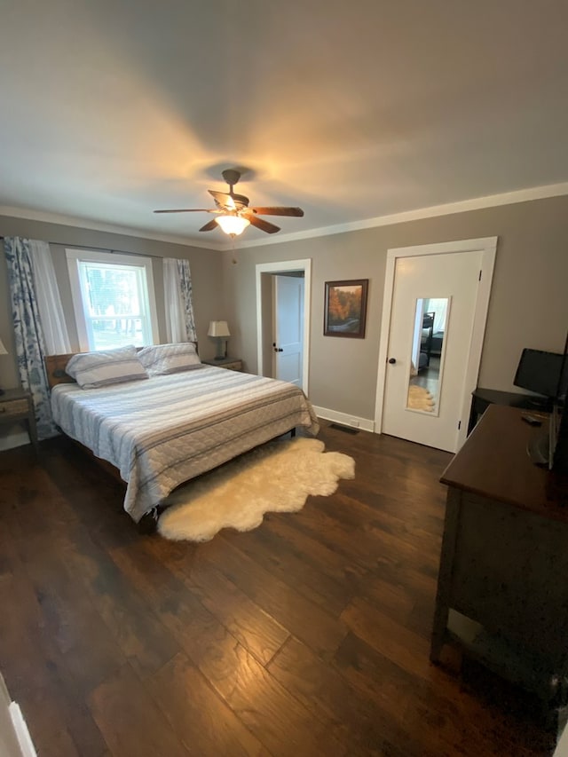 bedroom featuring dark wood-style flooring, crown molding, baseboards, and ceiling fan