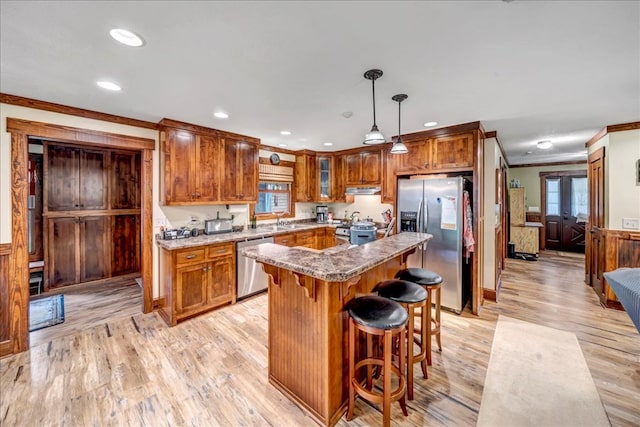 kitchen featuring a kitchen island, decorative light fixtures, stainless steel appliances, light hardwood / wood-style floors, and ornamental molding