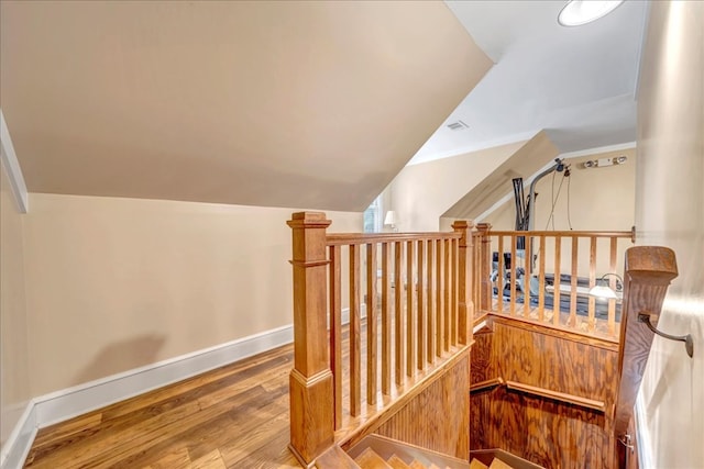 stairs featuring hardwood / wood-style floors and lofted ceiling