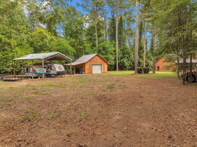 view of yard featuring a garage, an outbuilding, and a carport