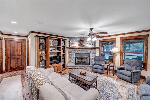 living room with a fireplace, hardwood / wood-style flooring, ceiling fan, and crown molding