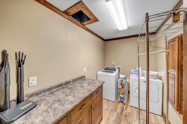 laundry area featuring light wood-type flooring, ornamental molding, a textured ceiling, and washer and dryer