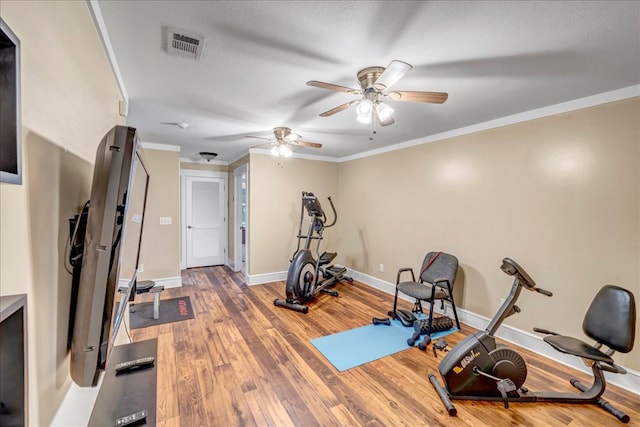 workout area featuring hardwood / wood-style flooring, a textured ceiling, ceiling fan, and ornamental molding