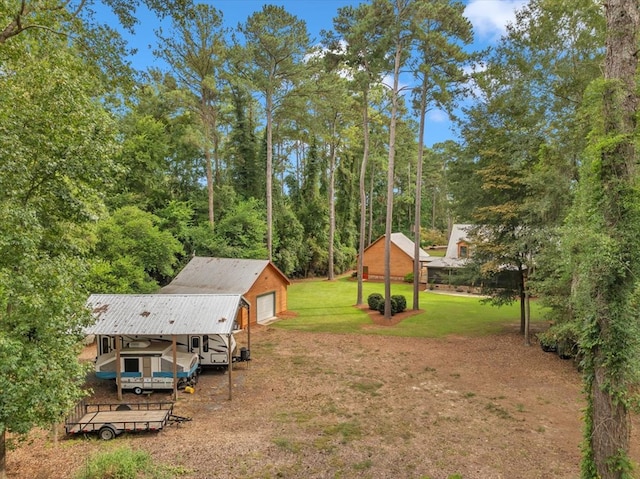 view of yard featuring an outdoor structure, a carport, and a garage