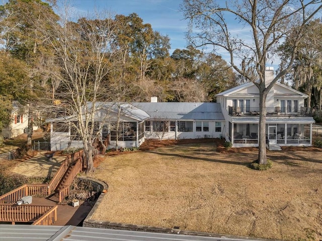 view of front of house featuring a chimney, a front yard, a balcony, and a sunroom