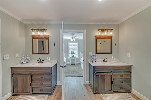 ensuite bathroom with wood finished floors, two vanities, a sink, and crown molding