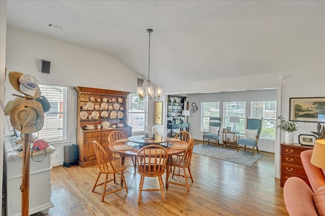 dining area with lofted ceiling, light wood finished floors, visible vents, and a chandelier