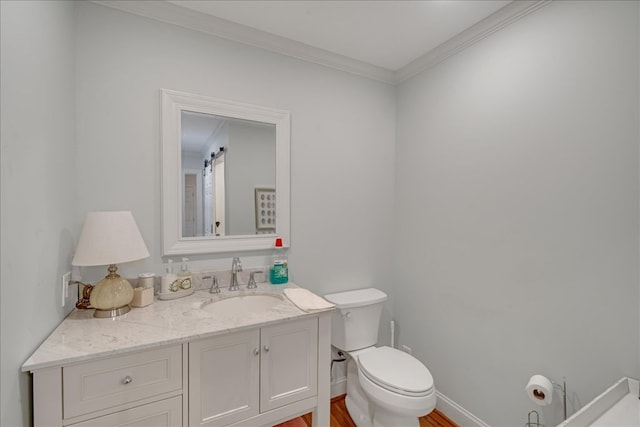 bathroom featuring crown molding, toilet, vanity, wood finished floors, and baseboards