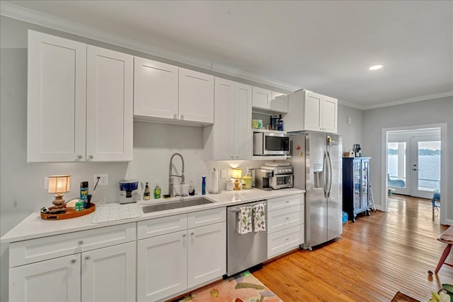 kitchen with white cabinets, appliances with stainless steel finishes, crown molding, french doors, and a sink