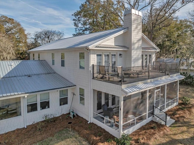 rear view of property with a sunroom, metal roof, a chimney, and french doors