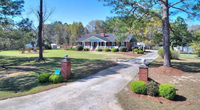 view of front of property with a front yard, a storage shed, and a porch