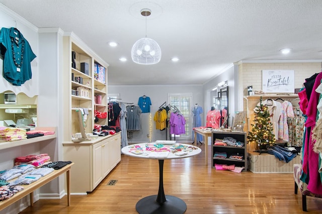 rec room featuring a textured ceiling, light hardwood / wood-style flooring, and ornamental molding