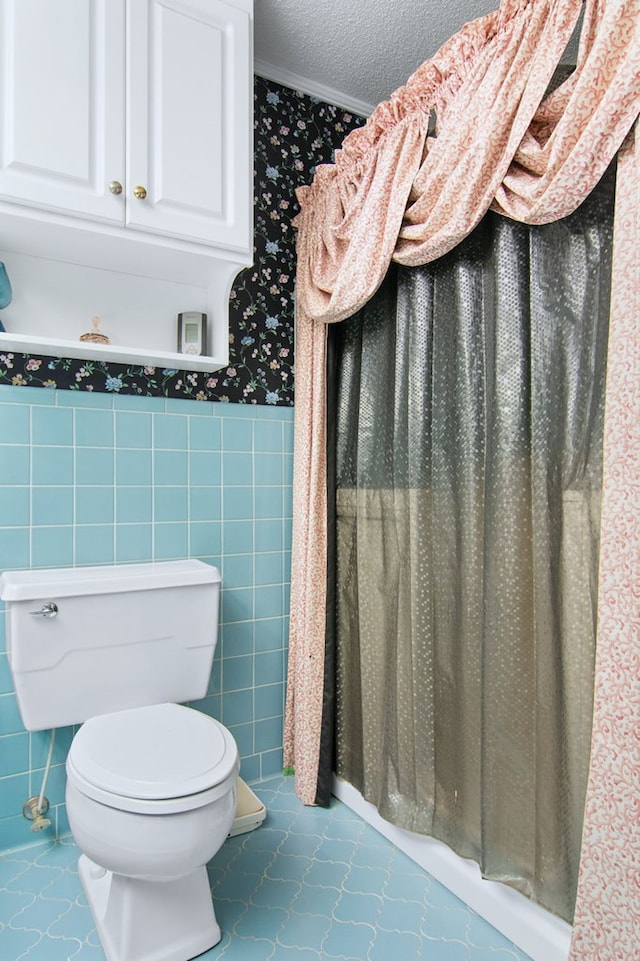 bathroom featuring tile patterned flooring, tile walls, a textured ceiling, toilet, and ornamental molding