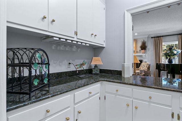 kitchen featuring white cabinets, a textured ceiling, and dark stone counters