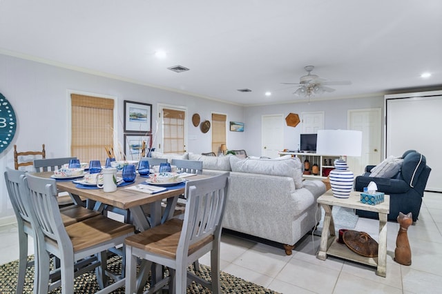 tiled dining space featuring crown molding and ceiling fan