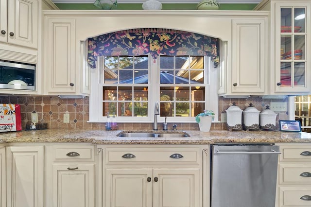 kitchen featuring sink, light stone counters, backsplash, and stainless steel appliances